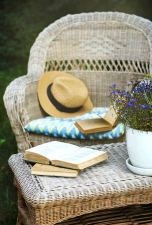 Wicker table, chairs and books in the garden at summer timeの写真素材