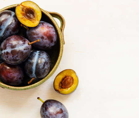 Fresh plums in bowl on wooden table, top view, copy spaceの写真素材