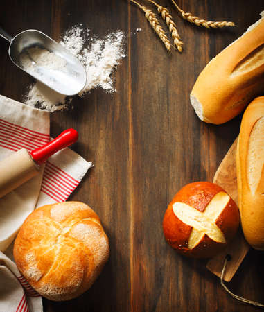 Assortment of baked bread, flour and roller pin on wooden background wiht copy spaceの写真素材