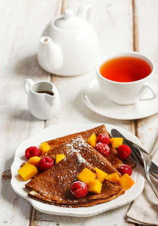 Crepes with fresh mango and raspberriesの写真素材