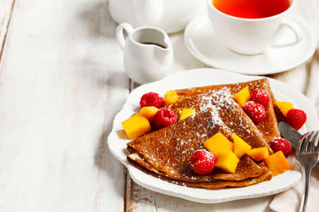 Crepes with fresh mango and raspberriesの写真素材