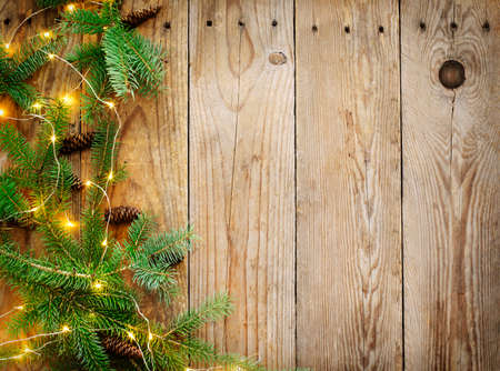 Christmas background with fir tree branches and lights on wooden board, copy spaceの写真素材