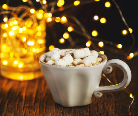 Hot chocolate with marshmallows against background with beautiful Christmas lights of bokehの写真素材