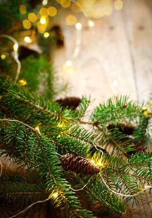 Christmas tree branches with lights on wooden background, copy spaceの写真素材