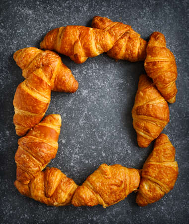 Fresh croissants on a dark grey background. Top view