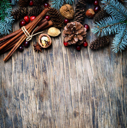 Christmas background with festive decorations, winter spices, cranberries, nuts and blue fir branches, top view, copy spaceの写真素材