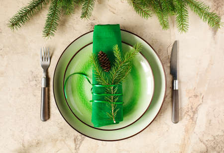 Two green empty round plates with napkin, fork and knife and Christmas decoration - fir tree brunch and cones, top view. Christmas menu backgroundの写真素材