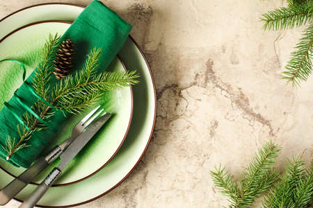 Two green empty round plates with napkin, fork and knife and Christmas decoration - fir tree brunch and cones, top view.の写真素材