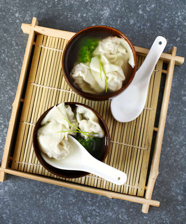 Chinese wonton soup with pork in black bowl, top viewの写真素材