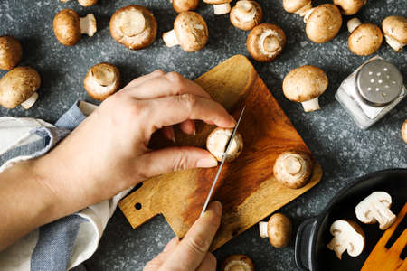 Fresh brown champignon mushrooms. Close up woman's hands cutting a fresh mushrooms, copy spaceの写真素材