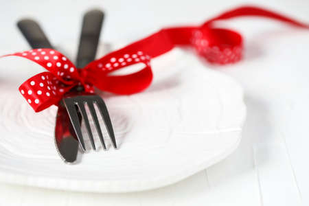 Fork and knife tied with a red ribbon on white background with copy space.の写真素材