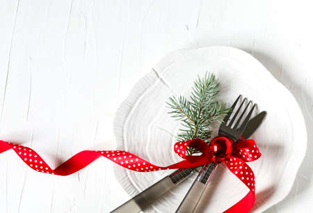 Fork and knife tied with a red ribbon and Christmas decor on white background with copy space. Food,...