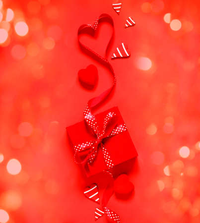 Gift box with red bow ribbon on red background for Valentines day, copy spaceの写真素材