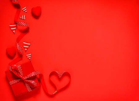 Gift box with red bow ribbon on red background for Valentines day, copy spaceの写真素材