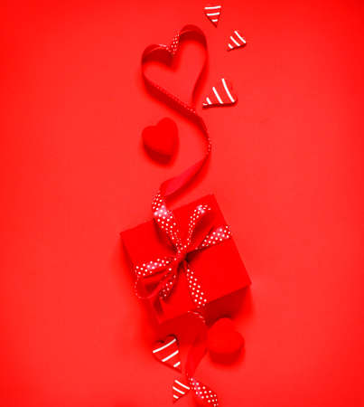 Gift box with red bow ribbon on red background for Valentines day, copy spaceの写真素材