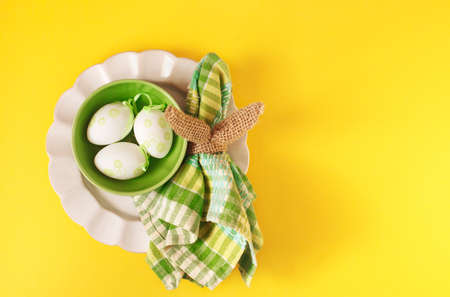 Happy Easter table setting with Easter decoration eggs on yellow background, top view, flat lay,...