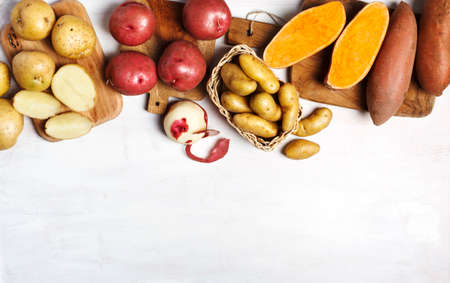 Variety of raw uncooked organic potatoes: red, white, sweet  and fingers potatoes over dark texture background. Top view, copy spaceの写真素材