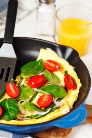 Omelette with green bean, spinach and tomato in a skillet.の写真素材