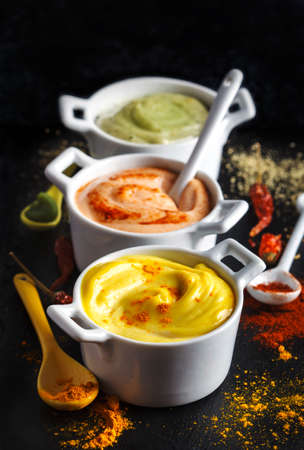 Vegan almonds mayonnaise with wasabi, chilli and turmeric in bowl on black background. Dairy, egg and soy-freeの写真素材