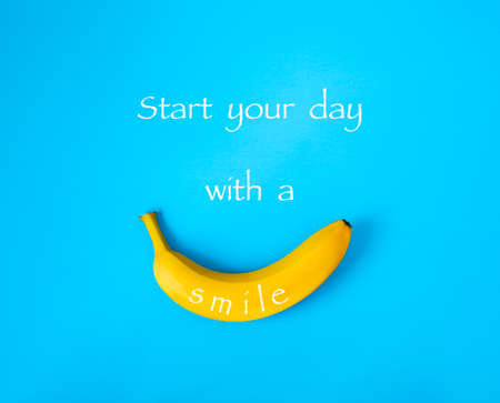 Ripe banana on blue background, text Start your day with a smile.の写真素材