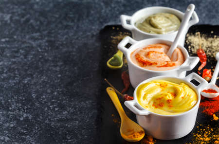 Vegan almonds mayonnaise with wasabi, chilli and turmeric in bowl on black background. Dairy, egg and soy-free.の写真素材