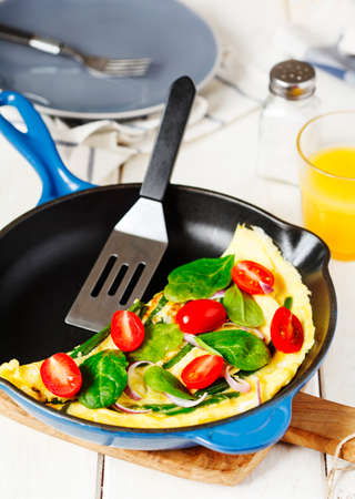 Omelette with green bean, spinach and tomato in a skillet.の写真素材