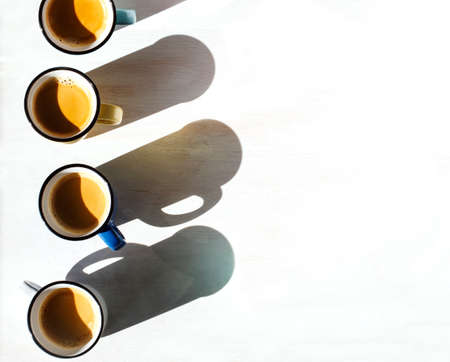 Cups of coffee. Four cups of Espresso on a table back lit by the sun casting a long shadowsの写真素材