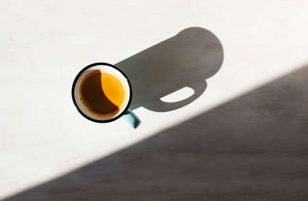 Cup of coffee. Ð¡up of Espresso on a table back lit by the sun casting a long shadowの写真素材