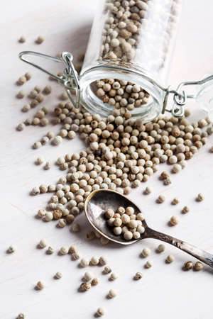 White peppers in jar and spoon on white backgroundの写真素材