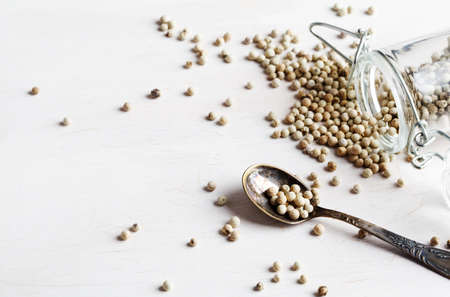 White peppers in jar and spoon on white background, copy spaceの写真素材