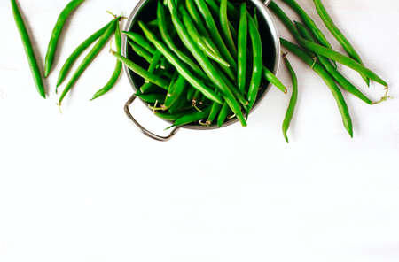 Green beans in bowl on white wooden background. Top view, copy space