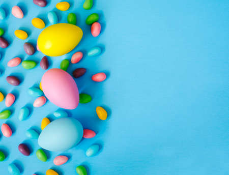 Easter decoration eggs and candy on blue background. Easter background, copy space