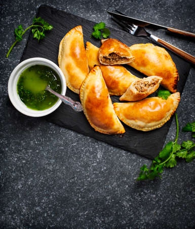 Empanadas with chimichurri sauce. Latin American tradition cuisine. Top view, copy spaceの写真素材