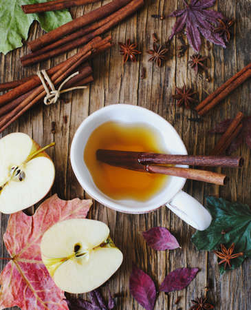 Hot drink (apple tea, sider, punch) with cinnamon stick, star anise and clove. Seasonal mulled drink on wooden background. Hot drink with apples for autumn or winter time. Autumn compositionの写真素材
