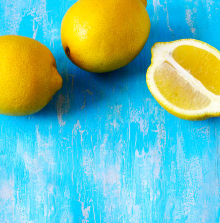 Fresh lemons on blue wooden background, frame, top view, copy spaceの写真素材