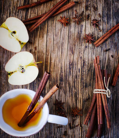 Hot drink (apple tea, sider, punch) with cinnamon stick, star anise and clove. Seasonal mulled drink on wooden background. Hot drink with apples for autumn or winter time. Autumn frame, copy spaceの写真素材