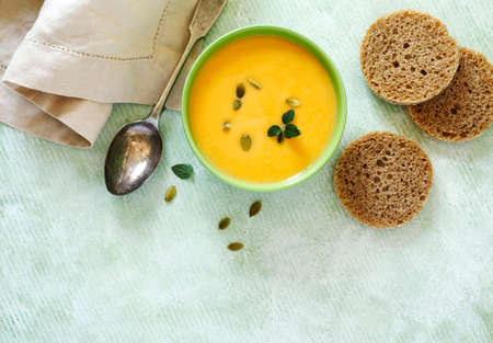 Pumpkin creamy soup on light green background. Top view, copy spaceの写真素材