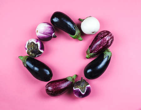 Fresh eggplants of different color and variety on a pink background, top view, copy spaceの写真素材