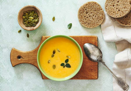 Pumpkin creamy soup on light green background. Top view.の写真素材