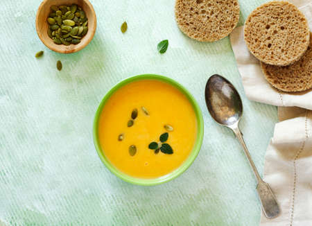 Pumpkin creamy soup on light green background. Top view.の写真素材