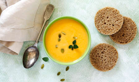 Pumpkin creamy soup on light green background. Top view, copy spaceの写真素材