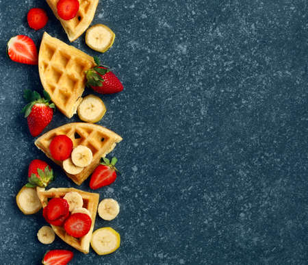 Belgian waffles with strawberries, banana and maple syrupの写真素材