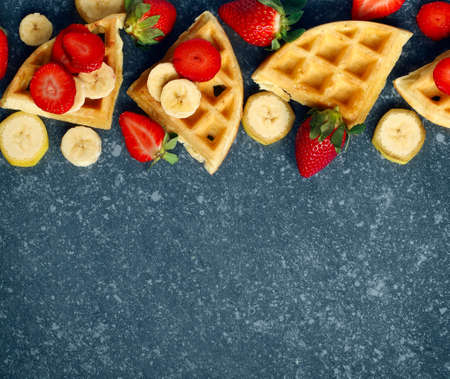 Belgian waffles with strawberries, banana and maple syrupの写真素材