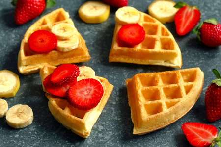 Belgian waffles with strawberries, banana and maple syrupの写真素材