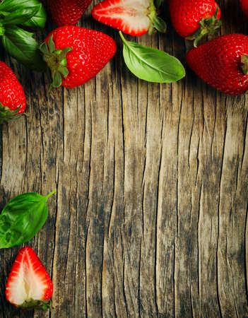 Fresh strawberries and basil. Strawberries and basil frame on wooden background, copy spaceの写真素材