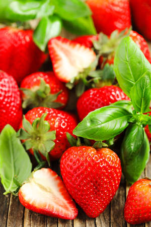 Fresh strawberries and basil leaves on wooden background.の写真素材