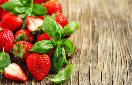 Fresh strawberries and basil leaves on wooden background.の写真素材