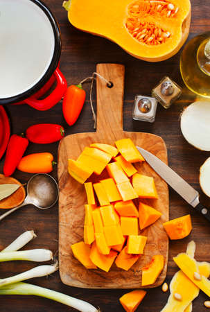 Preparing pumpkin, onions and sweet peppers for cooking around wooden cutting boardの写真素材