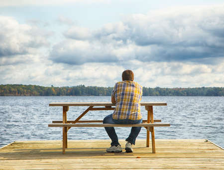 Man sitting on a bench in front of a lakeの写真素材