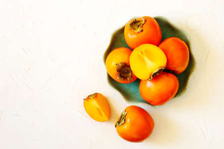Delicious fresh persimmon fruits in bowl, top viewの写真素材